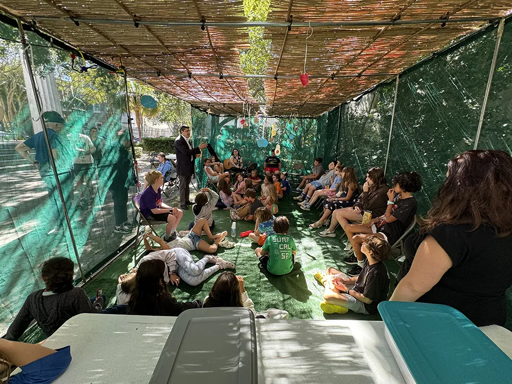 group of people sitting under a sukkah